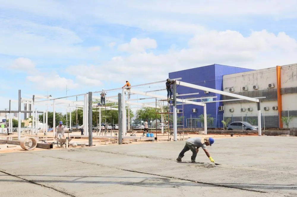 Equipes trabalham na conclusão da estrutura metálica do prédio, com a instalação de pilares, vigas e cobertura