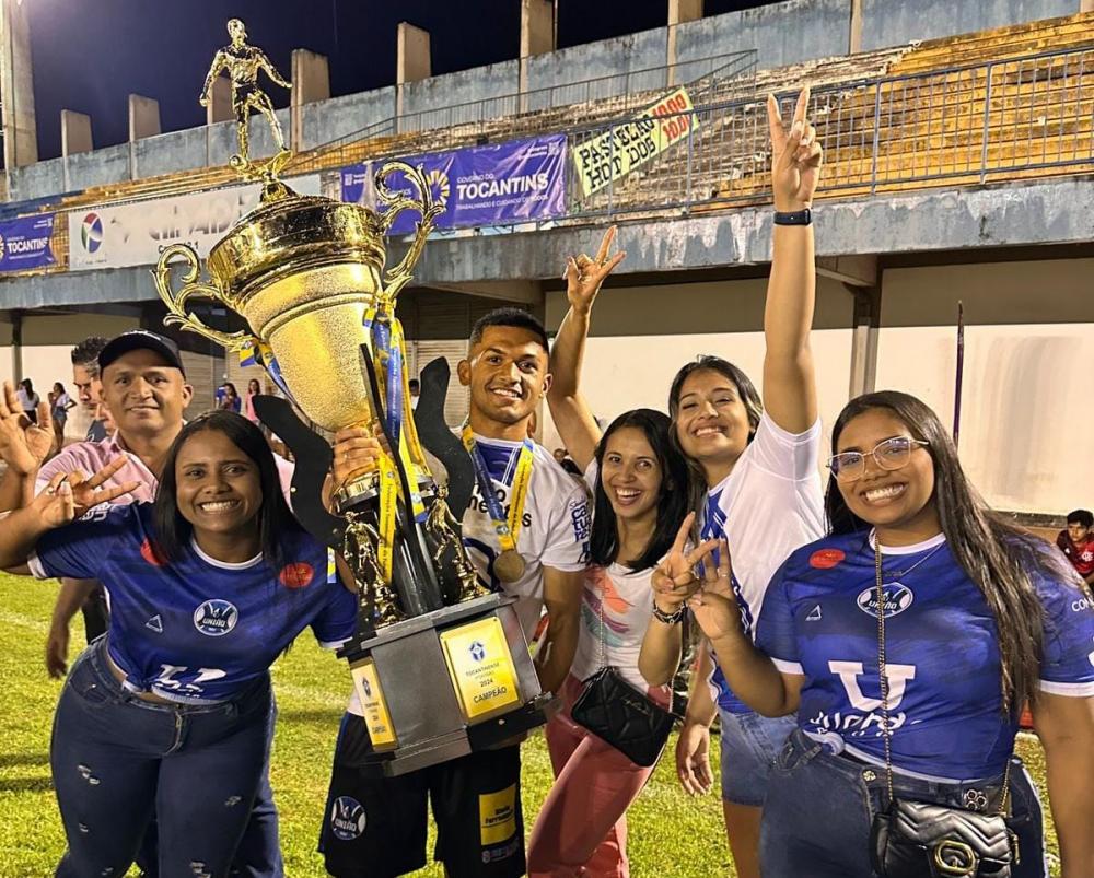 Segurando o troféu, o jovem atacante do União, Jhonatas Brasileiro, comemora o título com colegas de equipe e familiares.